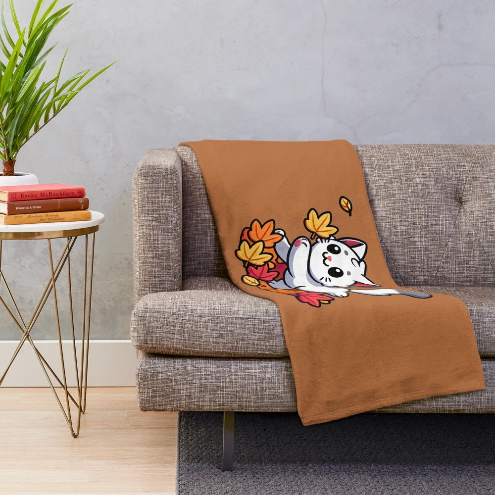 Cute cartoon cat playing with autumn leaves on a plush blanket