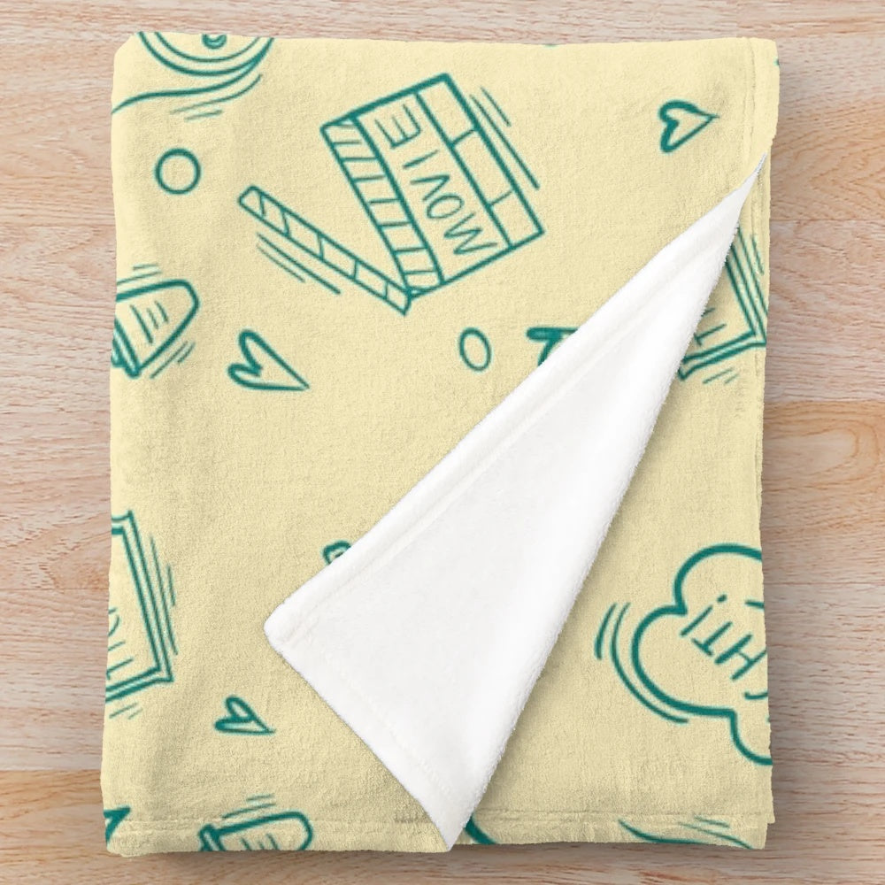Plush blanket with a cinema-themed pattern featuring movie elements like popcorn, cameras, and retro drinks.