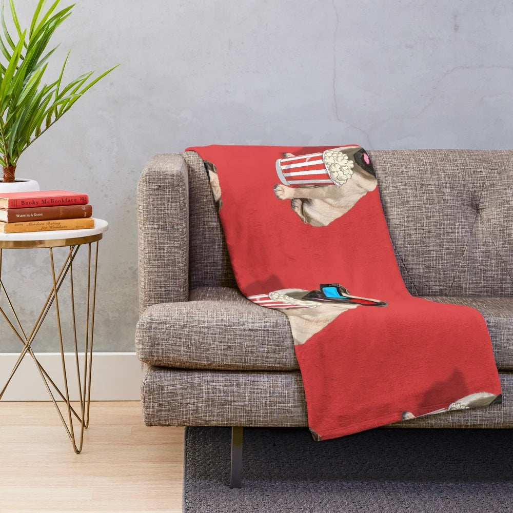 Adorable pug dog wearing glasses and holding popcorn on a plush cinema-themed blanket