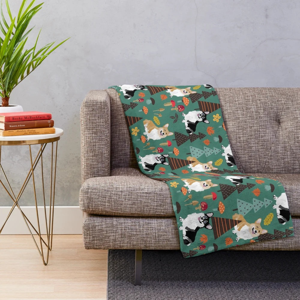 Corgis in a fall forest with mushrooms and flowers, dark teal plush blanket