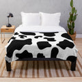 Soft and warm cow spots plush blanket perfect for a modern, preppy bedroom or living room.