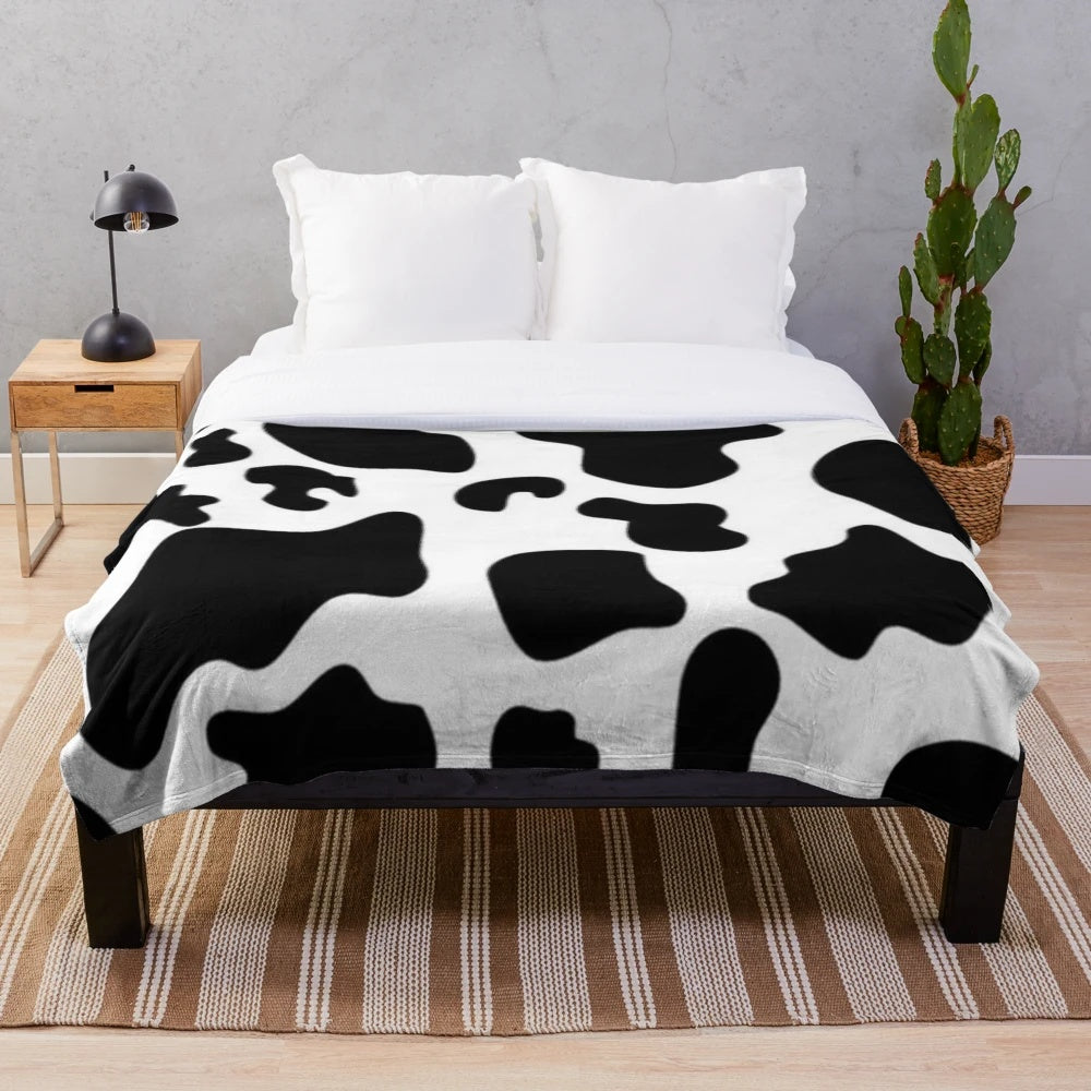 Soft and warm cow spots plush blanket perfect for a modern, preppy bedroom or living room.