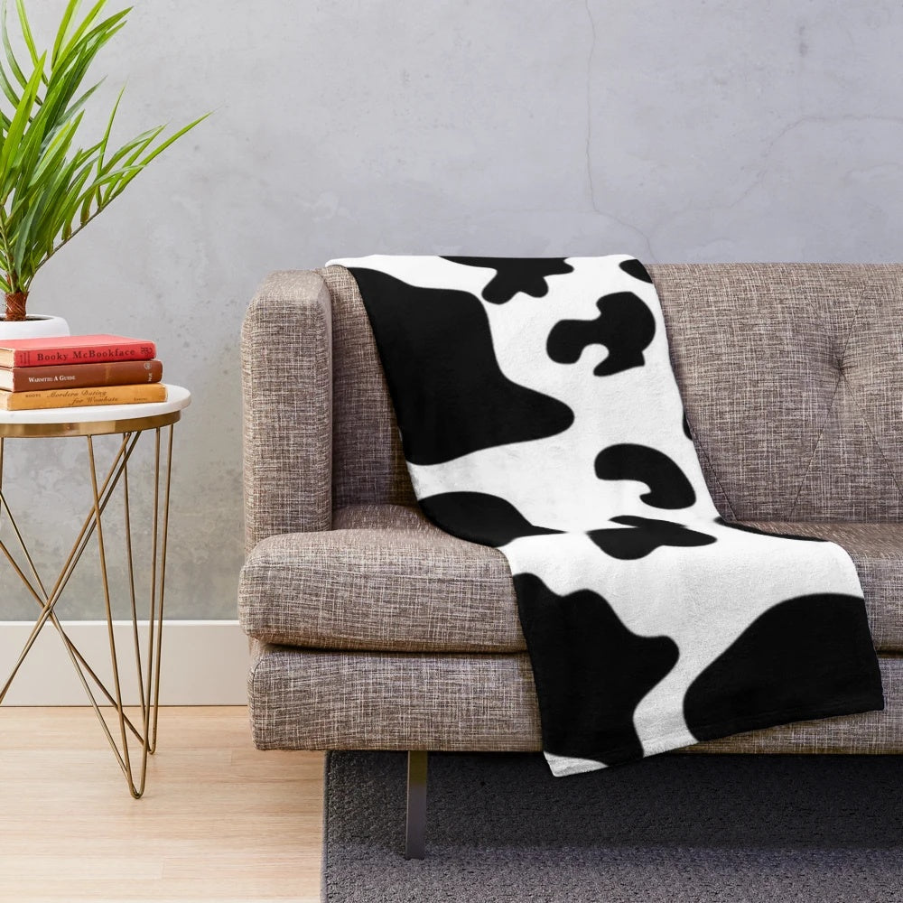 Soft and warm cow spots plush blanket perfect for a modern, preppy bedroom or living room.