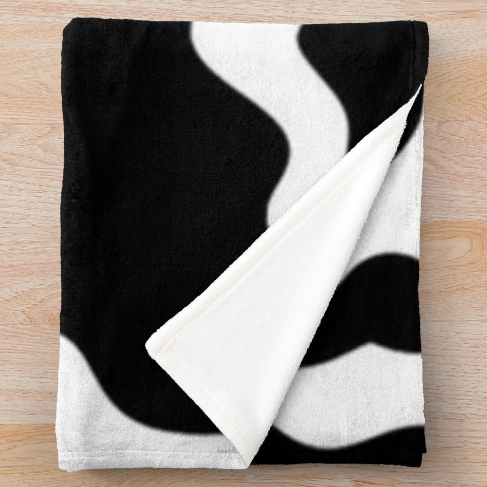 Soft and warm cow spots plush blanket perfect for a modern, preppy bedroom or living room.