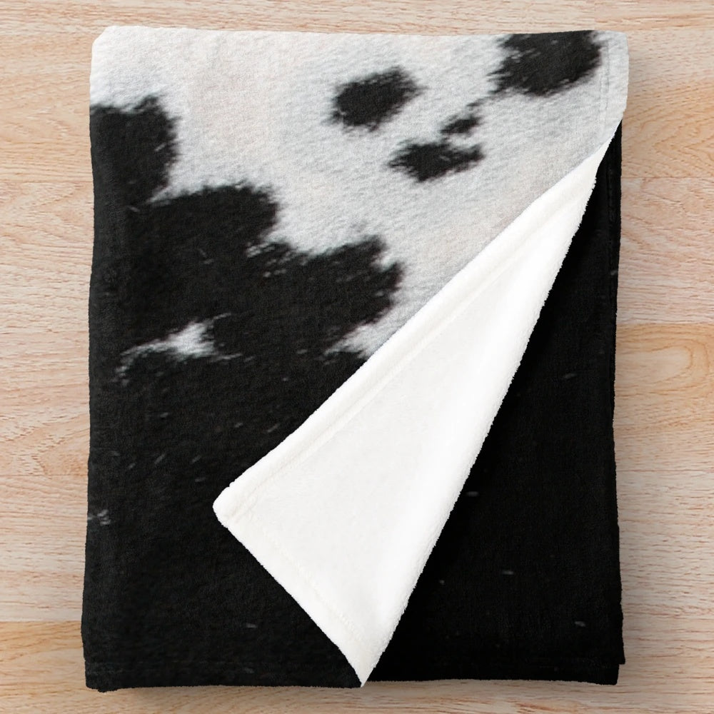 Cowhide plush blanket in a black and white spotted pattern
