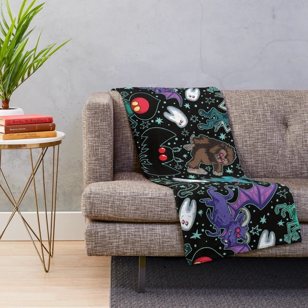 Cozy Cryptid Plush Blanket featuring various cryptid illustrations