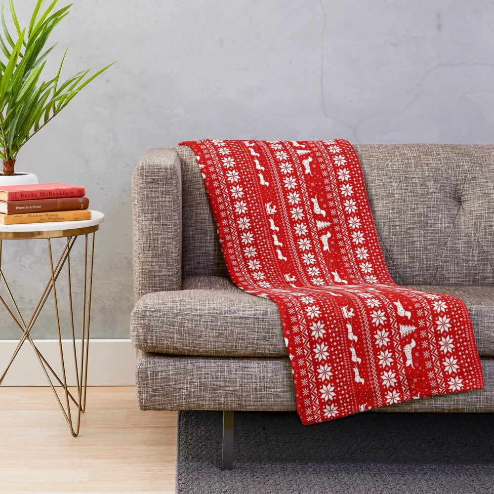 Dachshund dog wearing a Christmas sweater pattern on a plush blanket