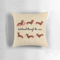 Dachshund Through The Snow Pillow featuring a dachshund dog wearing a Santa hat surrounded by Christmas decorations.