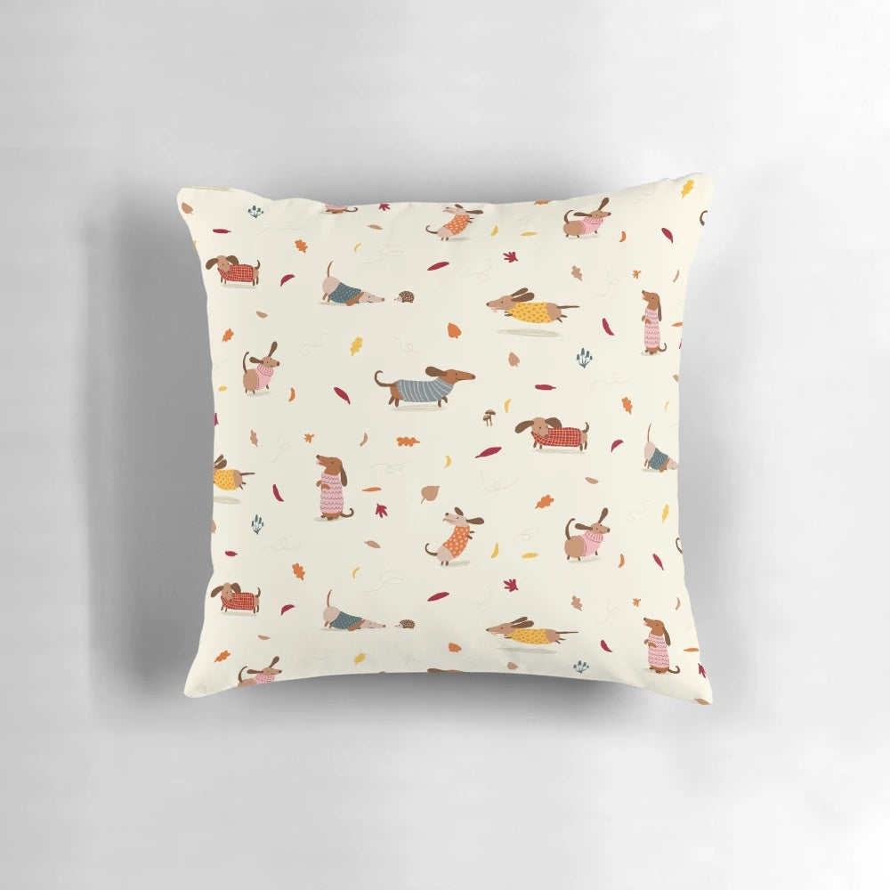 Cute dachshund wearing a winter sweater surrounded by autumn leaves on a decorative pillow