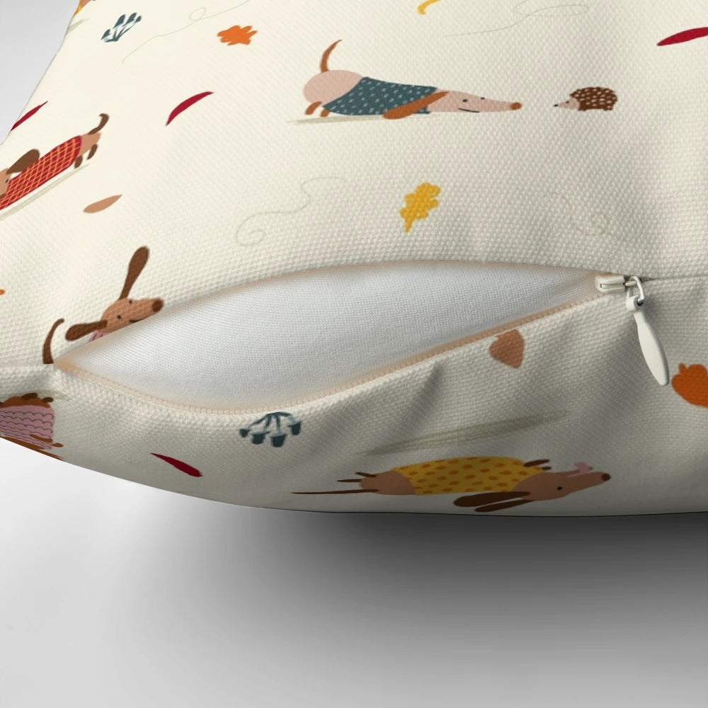 Cute dachshund wearing a winter sweater surrounded by autumn leaves on a decorative pillow