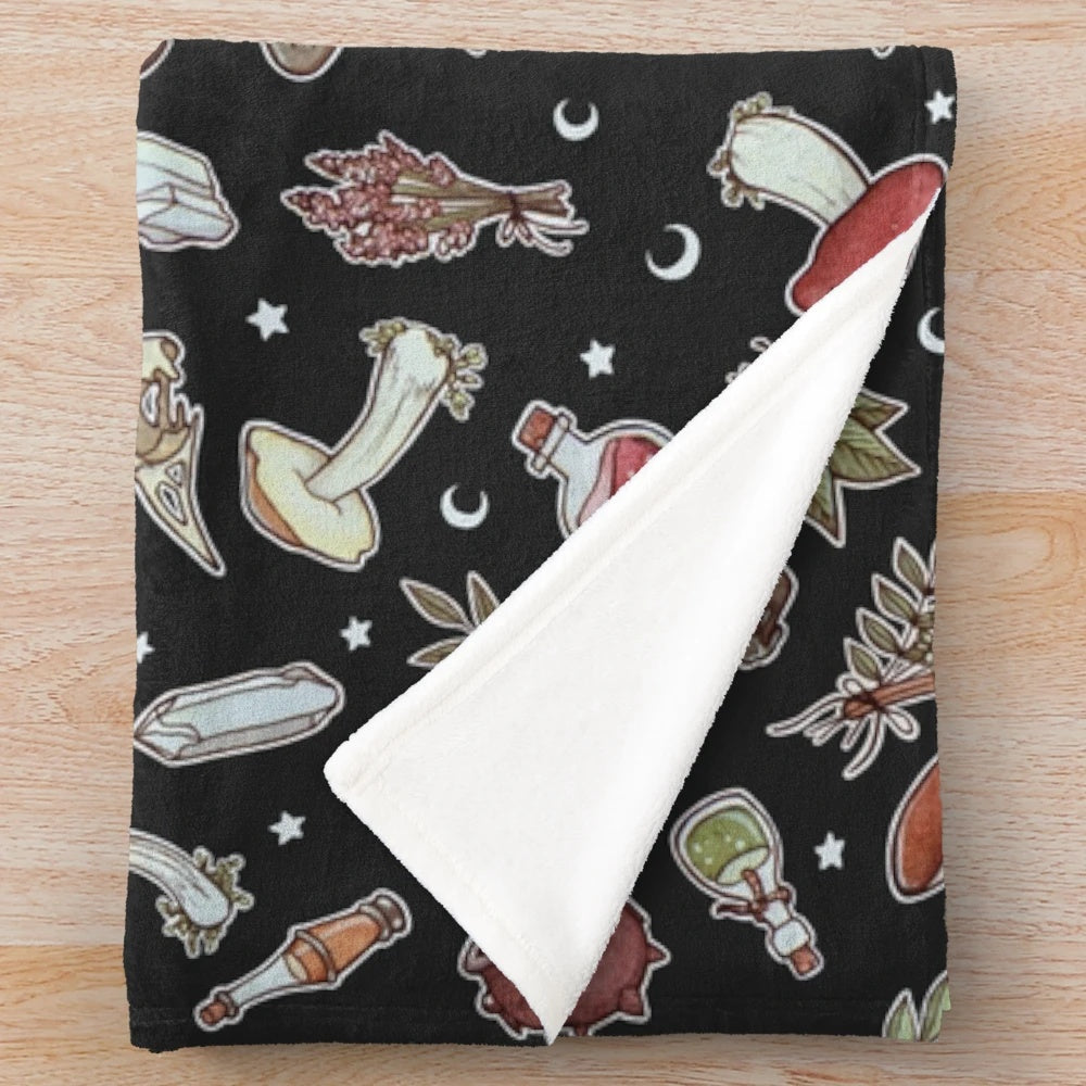 Dark plush blanket with a witchy pattern featuring moons, stars, and mushrooms