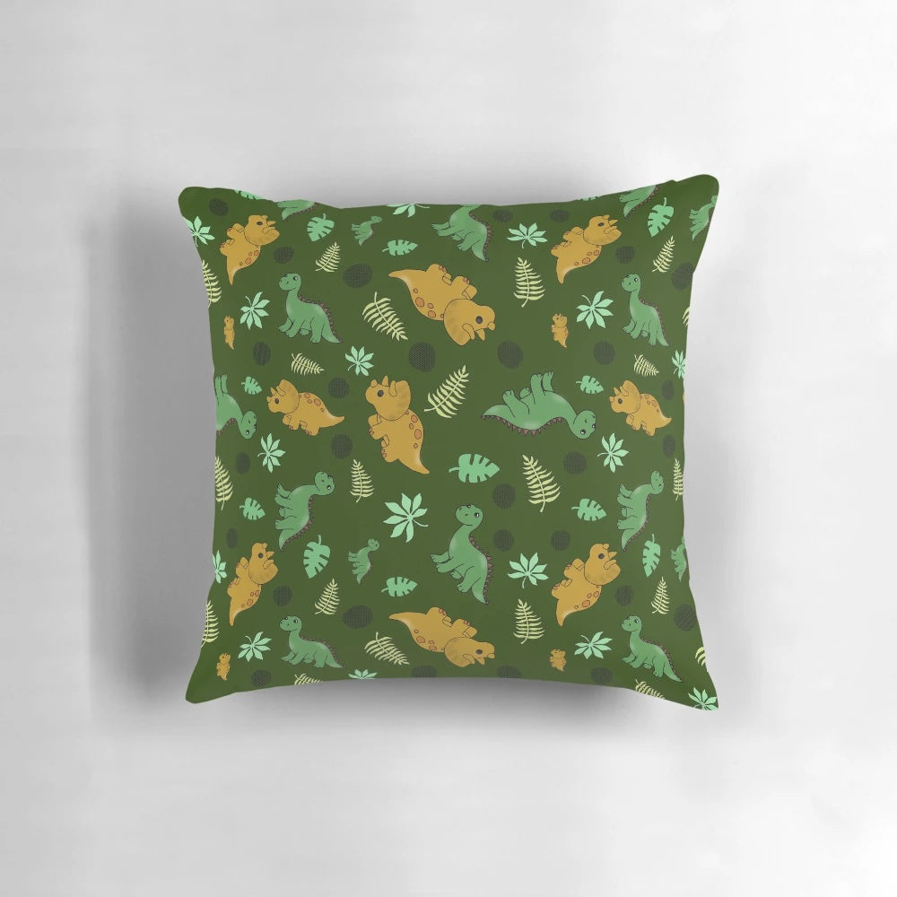A green pillow with a whimsical dinosaur pattern, featuring brontosaurus and triceratops.