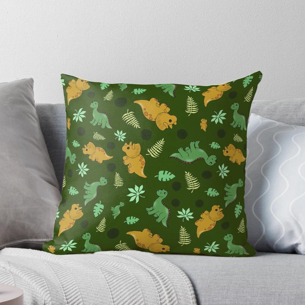 A green pillow with a whimsical dinosaur pattern, featuring brontosaurus and triceratops.