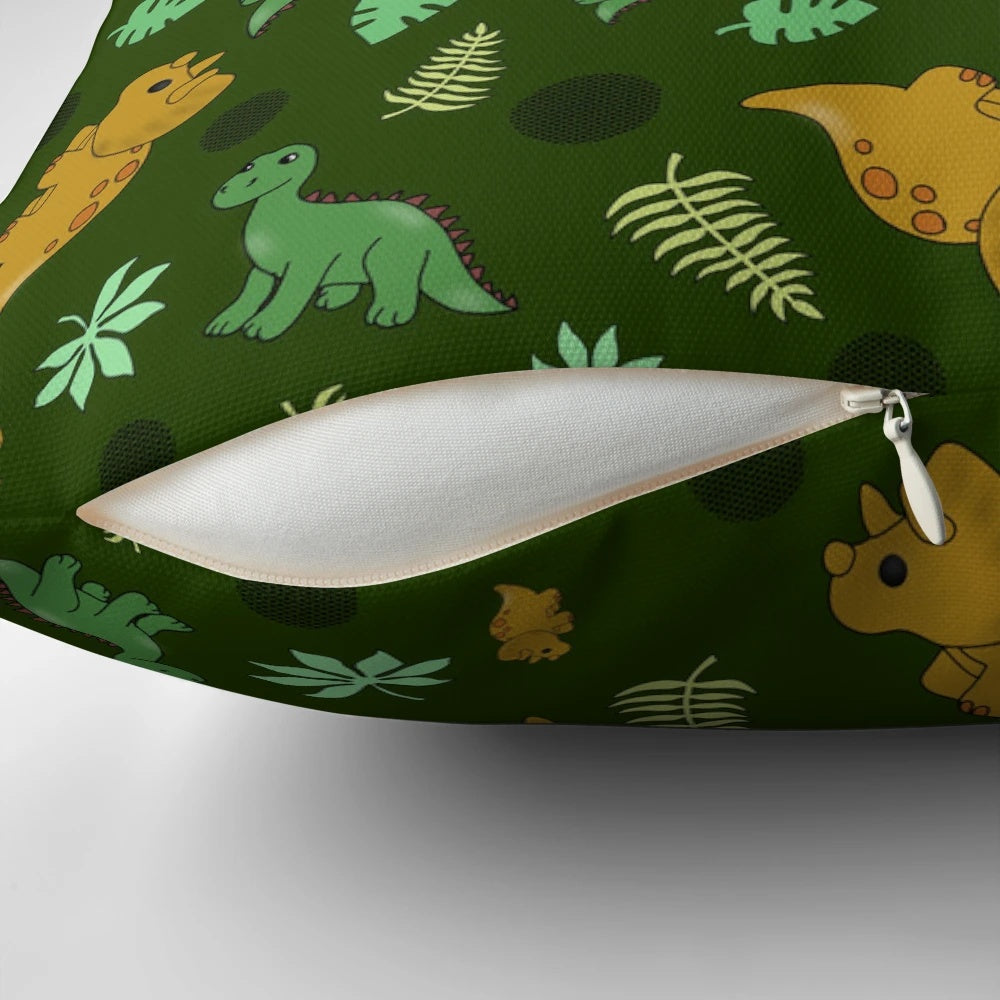 A green pillow with a whimsical dinosaur pattern, featuring brontosaurus and triceratops.