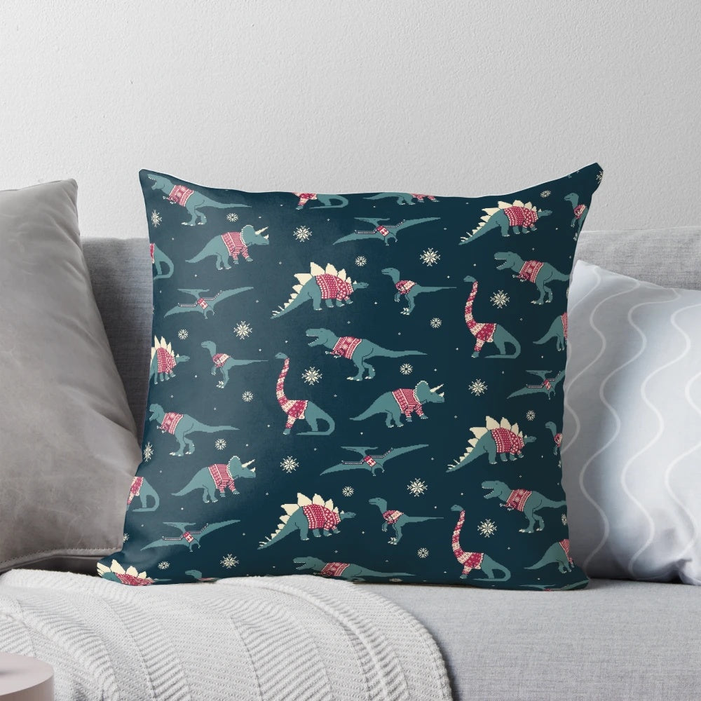 A decorative pillow featuring cute cartoon dinosaurs wearing colorful holiday sweaters.