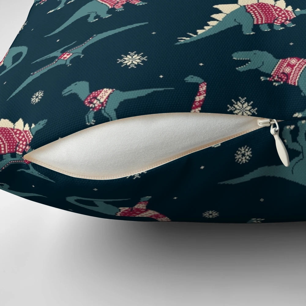 A decorative pillow featuring cute cartoon dinosaurs wearing colorful holiday sweaters.