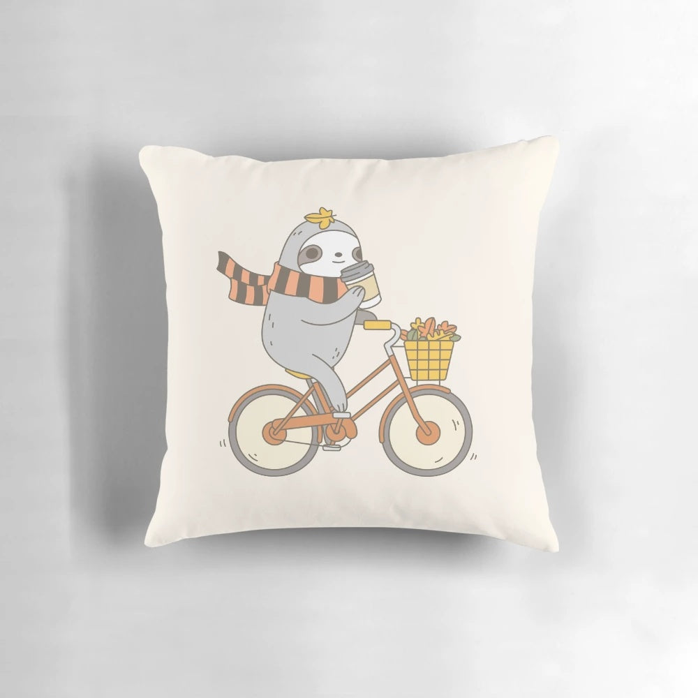A plush, autumn-themed pillow featuring a cute and whimsical sloth riding a bike, perfect for home decor or gift-giving.