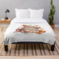 Plush fall-themed blanket with leaves, pumpkins, and other autumn elements