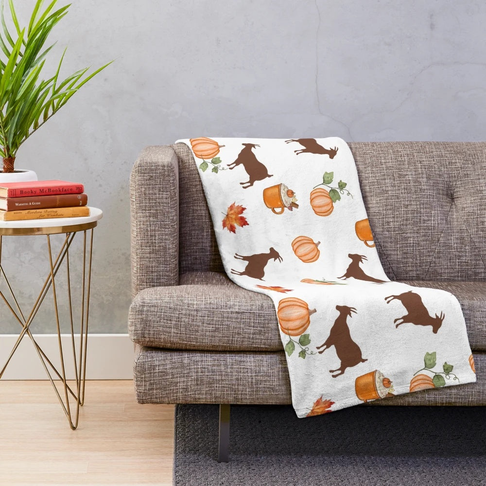 Plush blanket with autumn themed design of pumpkins, goats, and maple leaves