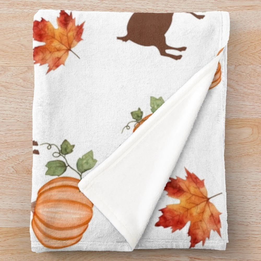 Plush blanket with autumn themed design of pumpkins, goats, and maple leaves