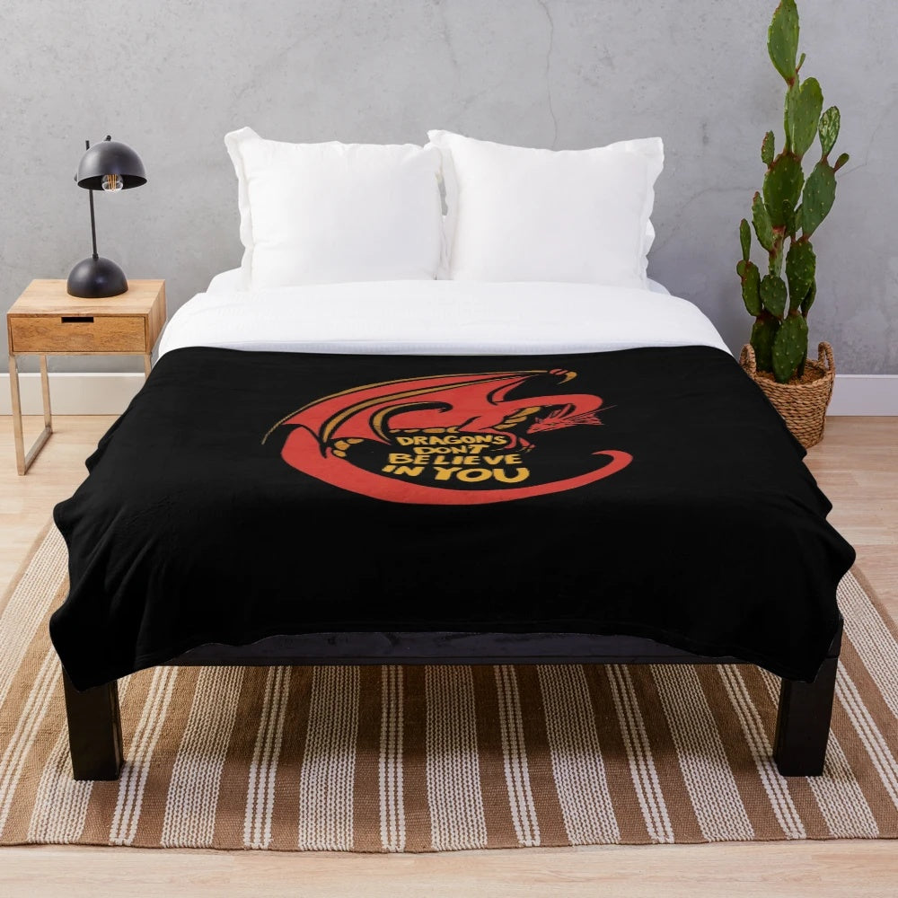 A plush red dragon-themed blanket with the text "Dragons don't believe in you