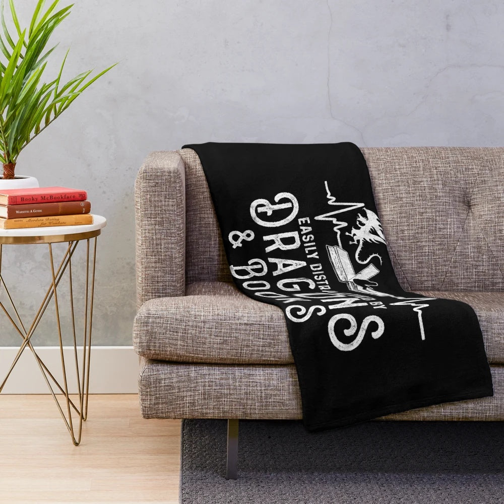 Girl reading fantasy book on cozy plush blanket with dragons