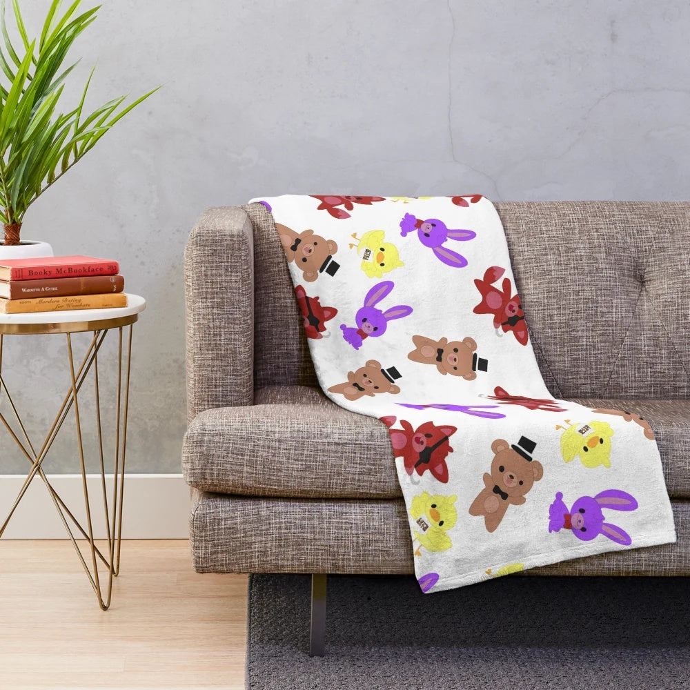 Cozy FNAF-inspired plush blanket with a cute, whimsical pattern featuring Freddy, Bonnie, Chica, and Foxy.