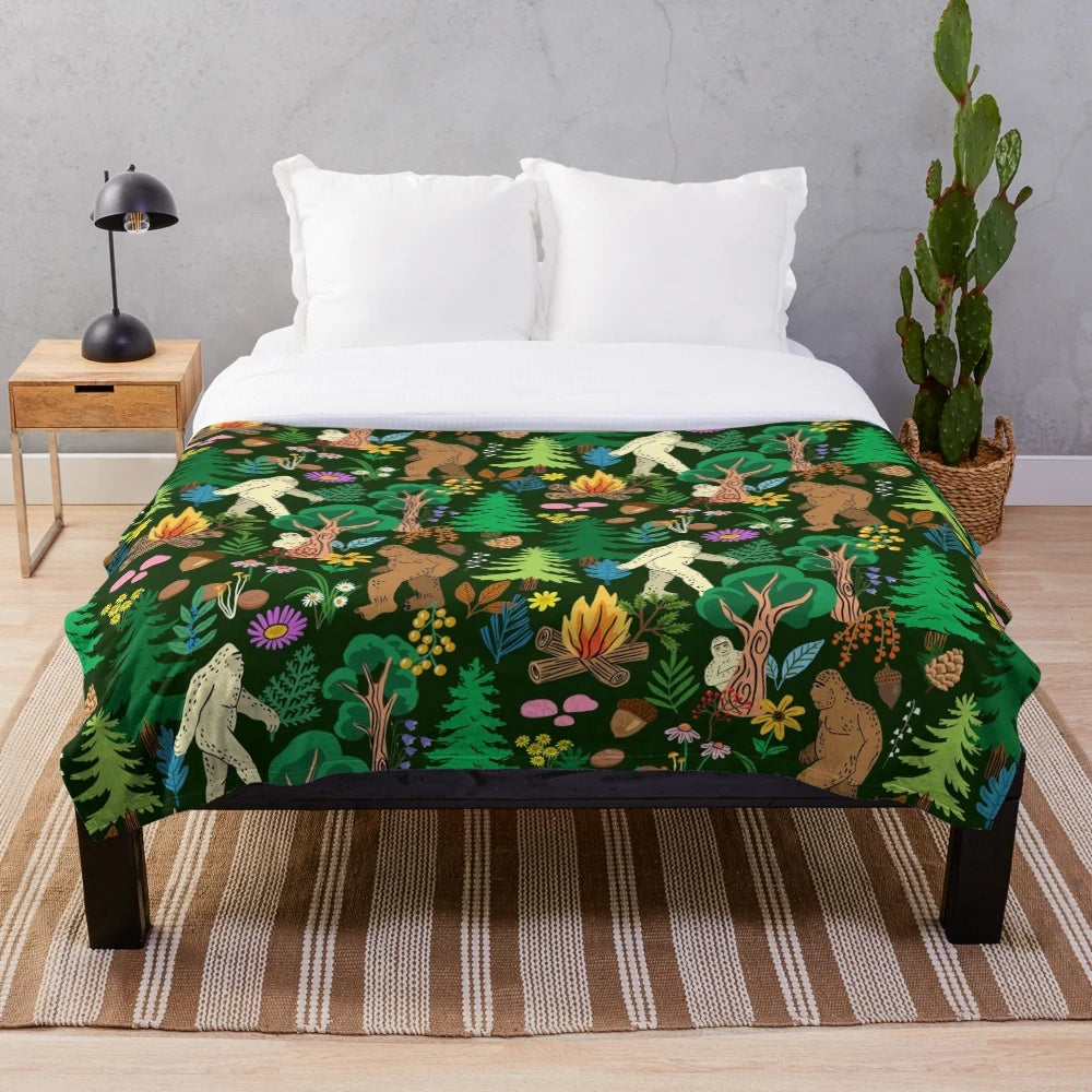 A cozy plush blanket featuring a forest scene with bigfoot, sasquatch, and other nature elements.