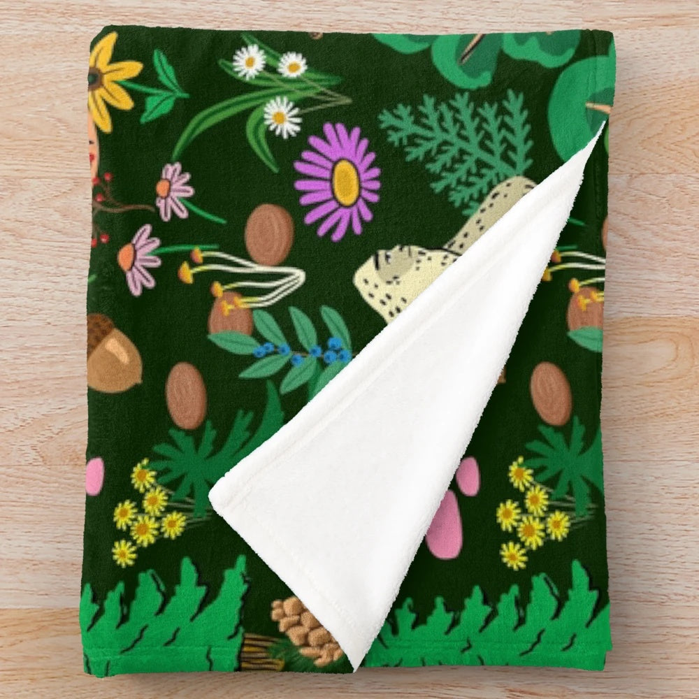 A cozy plush blanket featuring a forest scene with bigfoot, sasquatch, and other nature elements.