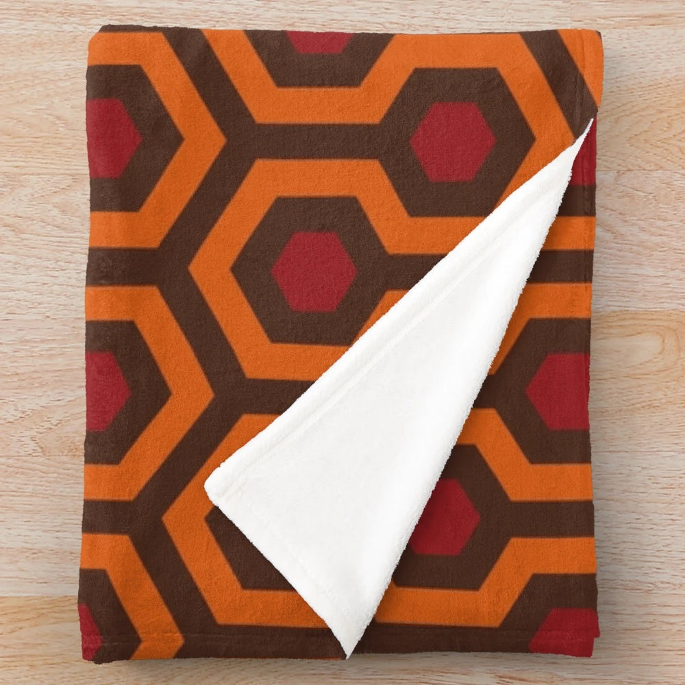 Geometric hexagon pattern plush blanket in orange, red, and brown colors
