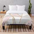 Soft and plush geometric patterned blanket in pink, grey, and gold colors