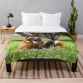 German Shepherd dog resting on a plush blanket in a grassy park