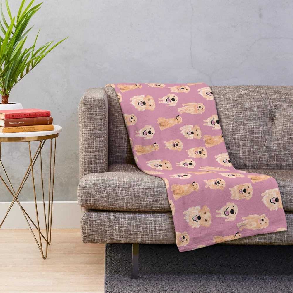 Golden retriever puppies on a soft pink plush blanket