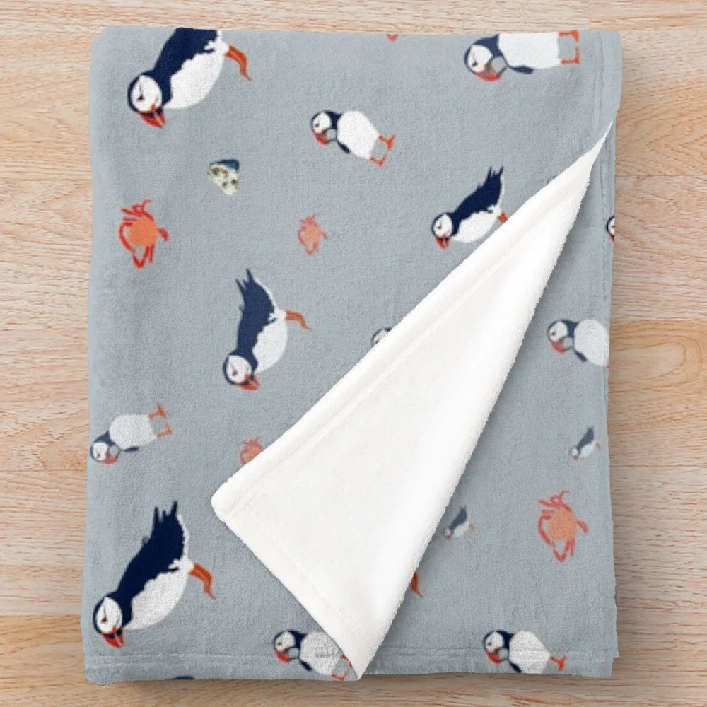 Grey plush blanket with a whimsical puffin bird pattern