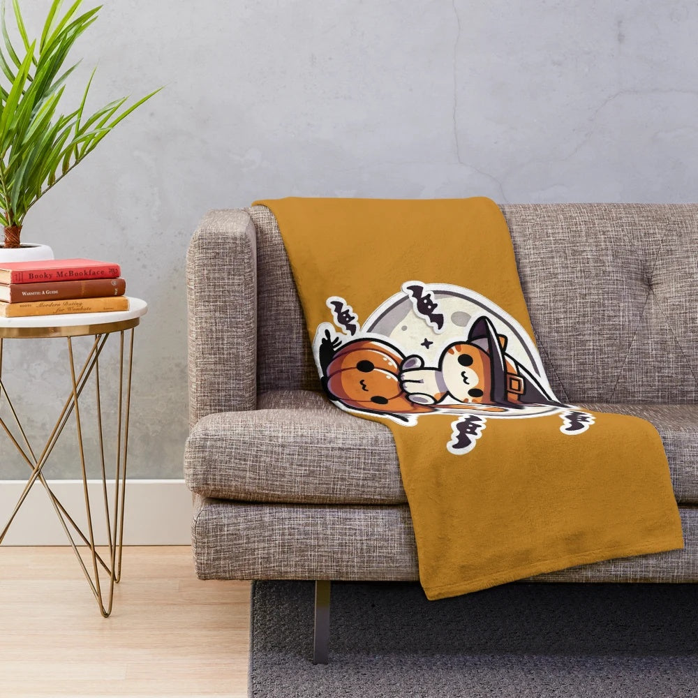 Cute Halloween cat sitting on a pumpkin on a plush blanket