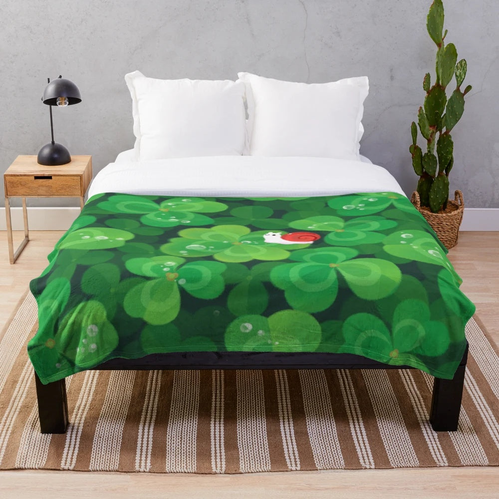 A cozy and soft plush blanket featuring a happy and lucky snail design with 4 leaf clovers and plants.