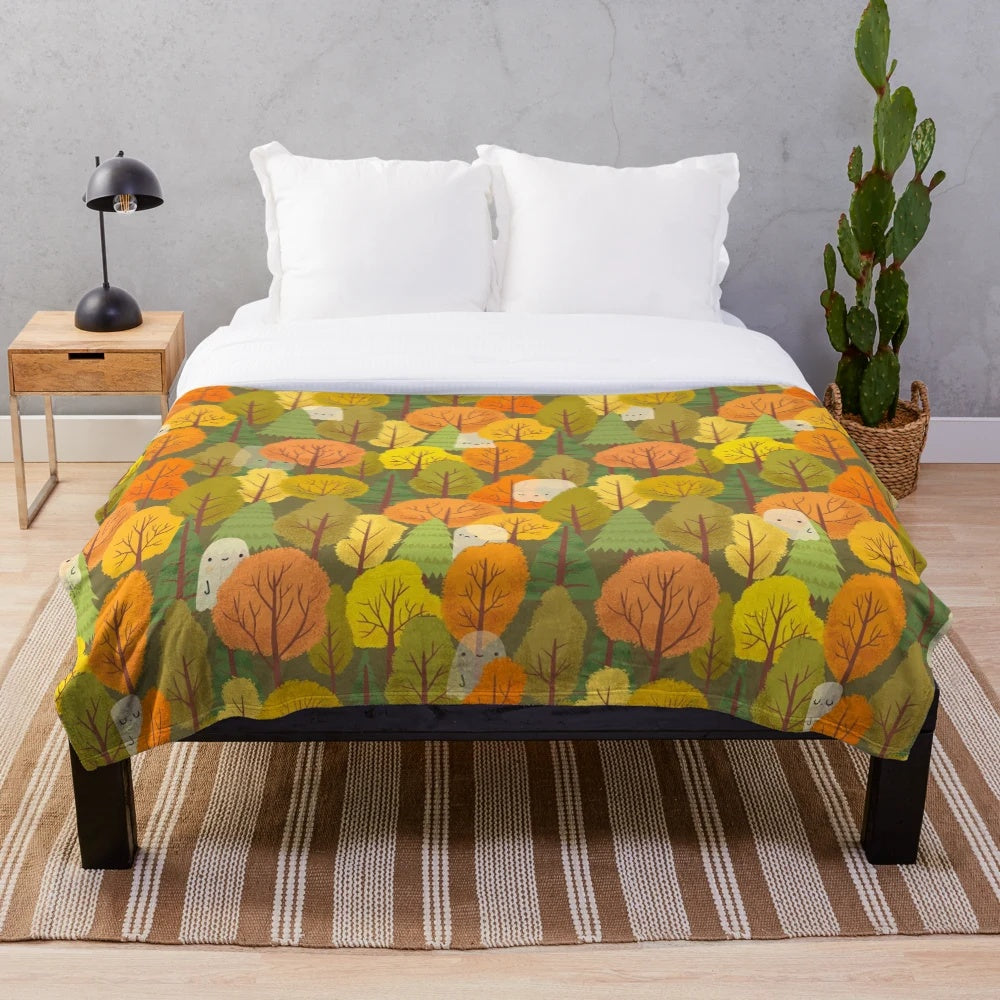Plush blanket with a design of cute ghosts and trees in an autumnal forest