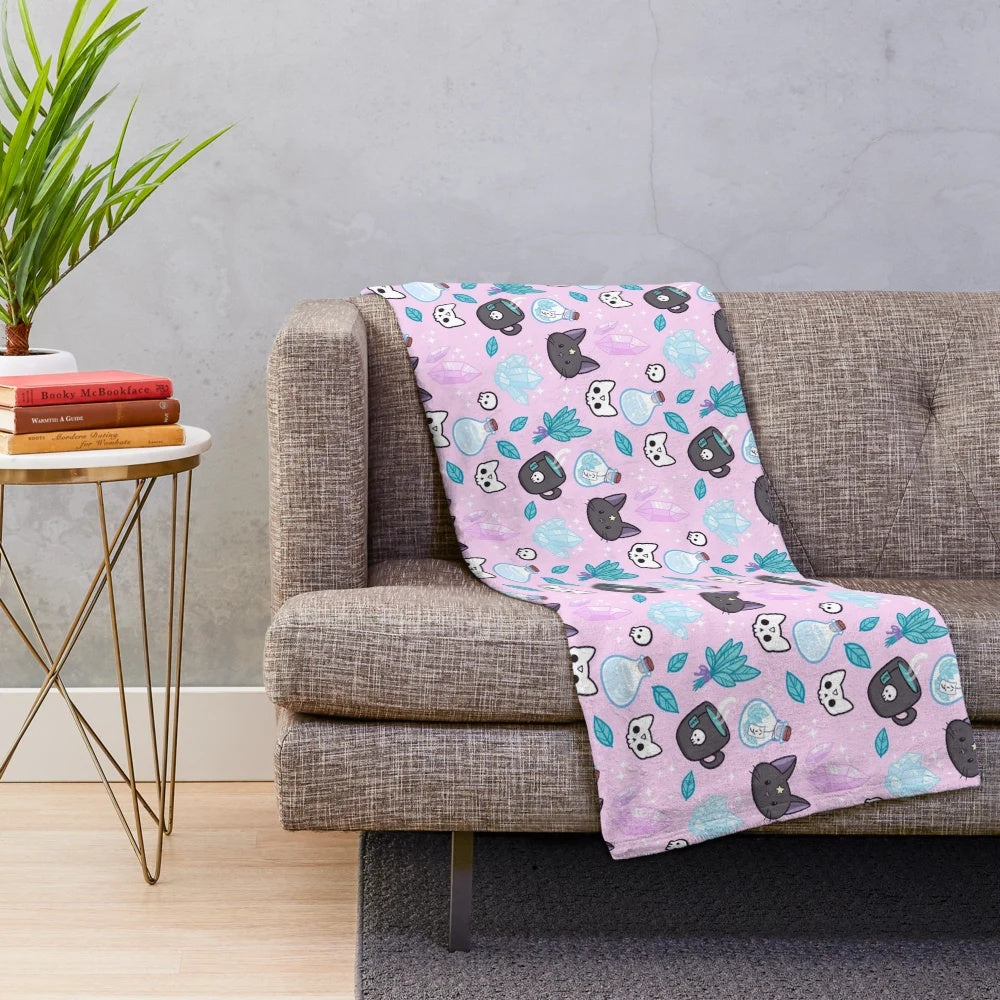 Soft and plush pink blanket with a witchy herb witch design featuring a cat skull and crystal cluster