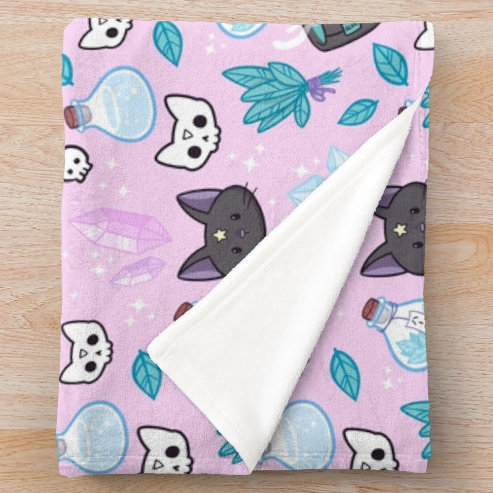 Soft and plush pink blanket with a witchy herb witch design featuring a cat skull and crystal cluster
