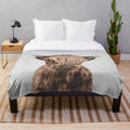 Soft and cuddly plush blanket featuring a cute highland calf design