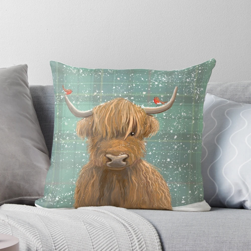A plush, high-quality pillow featuring a highland cow in a snowy tartan pattern with robins.