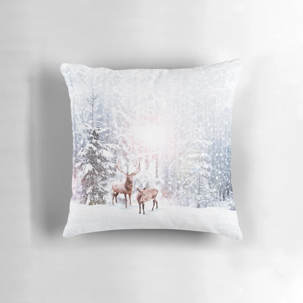 A cozy winter wonderland throw pillow with a deer stag design, surrounded by snowy trees.