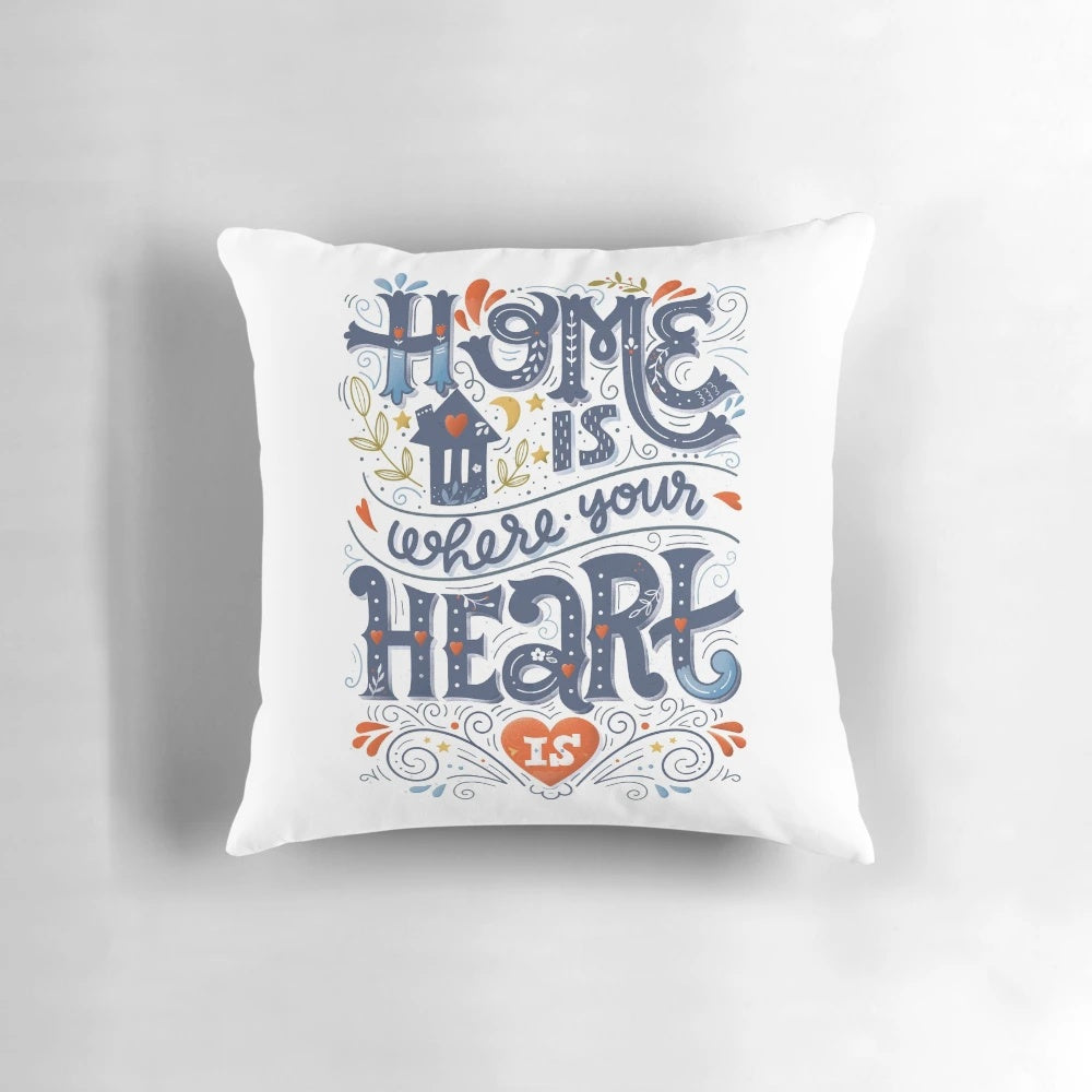 A decorative throw pillow with the inspirational quote "Home is where your heart is" in a handwritten typography design.