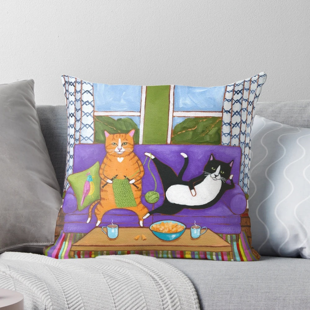 Knitted cats pillow in a cottage core style, featuring orange and tuxedo cats napping on a couch