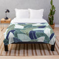 Plush blanket featuring a leaf wall design in navy blue, pine, and sage green