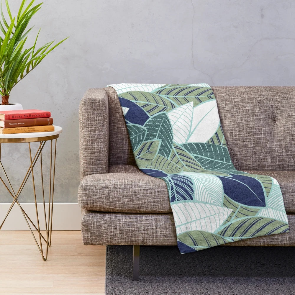 Plush blanket featuring a leaf wall design in navy blue, pine, and sage green