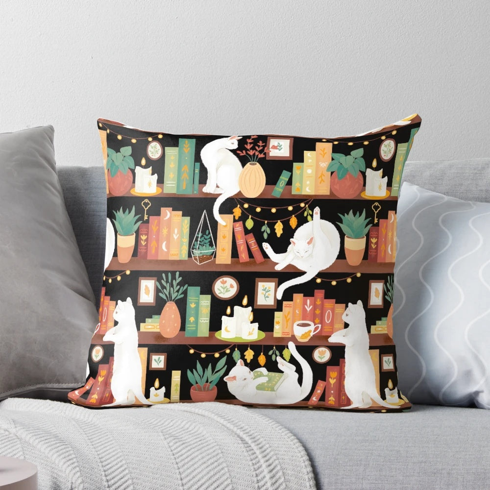 A cozy black and white cat sleeping on a bookshelf pillow with books, candles, and a cup of tea