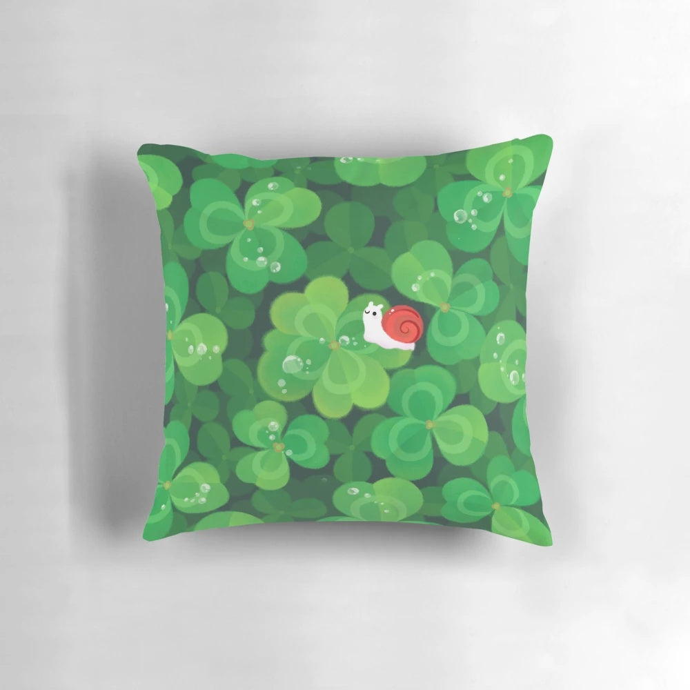 A soft, plush pillow featuring a happy, smiling snail sitting on a 4-leaf clover