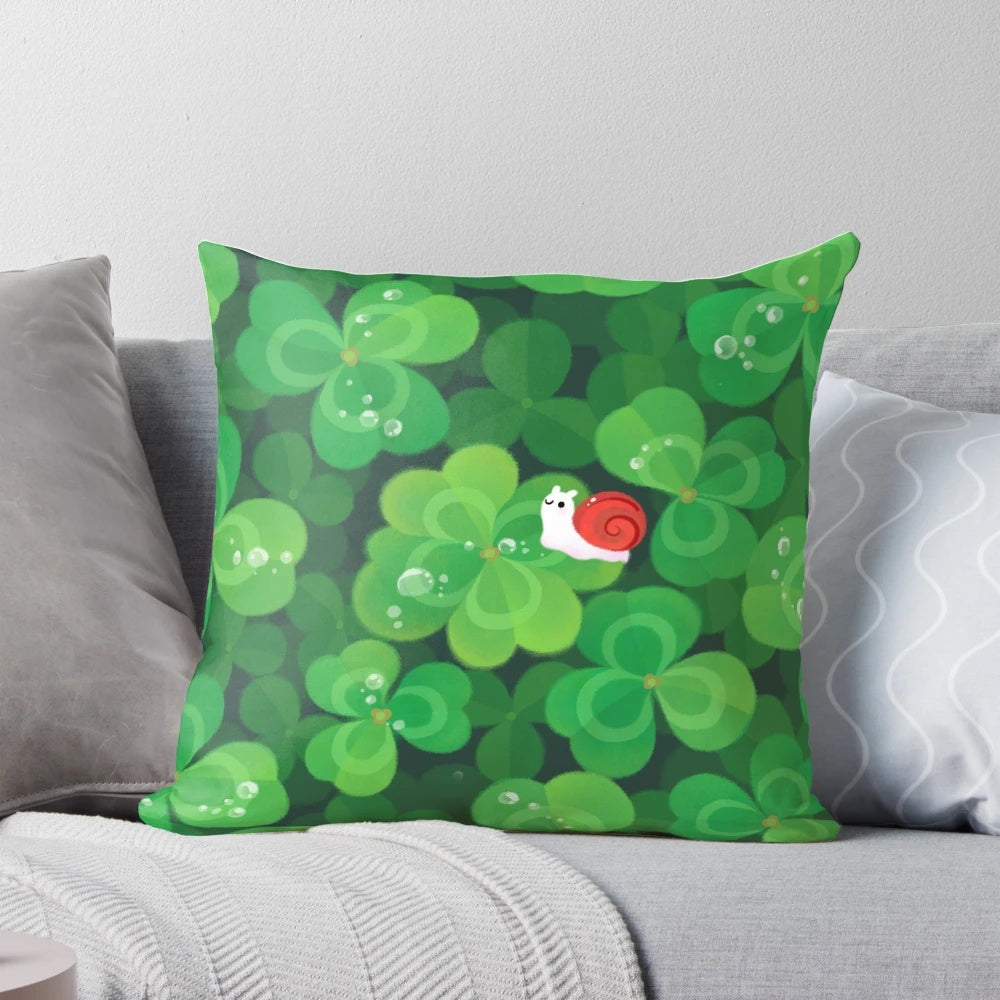 A soft, plush pillow featuring a happy, smiling snail sitting on a 4-leaf clover