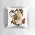 Close-up of an orange tabby cat curled up on a pillow with colorful maple leaves, perfect for fall decor.